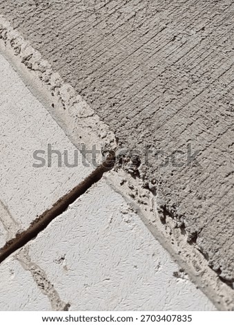 Detailed view of the junction between three rough concrete blocks. The upper right block has distinctive diagonal scratch marks..
