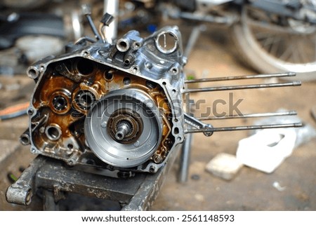 A detailed view of a motorcycle engine block being disassembled for repair and maintenance in a workshop, showcasing mechanical components and tools