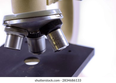 Detailed view of old microscope objective lenses with metal parts and focus mechanism on a white background.
