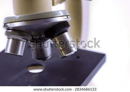 Detailed view of old microscope objective lenses with metal parts and focus mechanism on a white background.