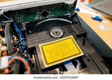 A detailed view of an open internal CD drive inside a device, revealing the circuit board, wiring, and disc mechanism components