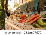 Detailed view of organic agricultural fresh produce in cardboard boxes placed on greenmarket stands with price tags. Closeup of locally grown colorful fruits and vegetables at farmers market booth.