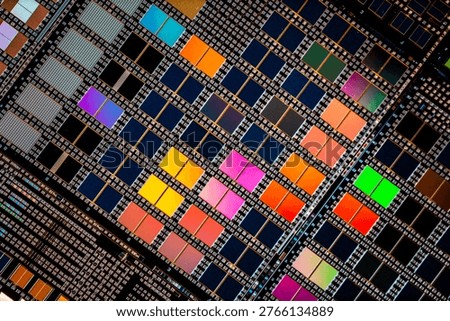 Detailed view of patterned silicon semiconductor wafer showing many integrated circuit dies in a geometric grid, colorful electronic texture for chip manufacturing and technology themes.