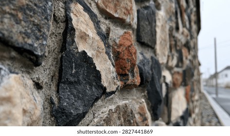 A detailed view of a rustic stone wall, showcasing the varied colors and rough textures of the natural rocks.