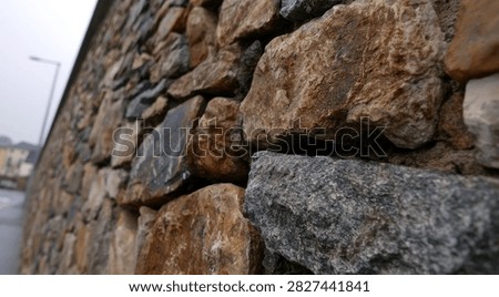 Detailed view of a rustic stone wall, showcasing the varied textures and colors of the natural rocks.