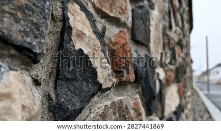 A detailed view of a rustic stone wall, showcasing the varied colors and rough textures of the natural rocks.