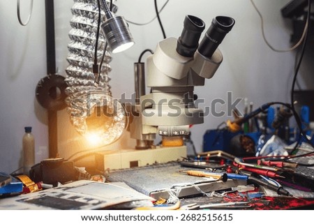 A detailed view of a scientific microscope surrounded by various tools on a cluttered lab table, showcasing the intricate environment of research and analysis.