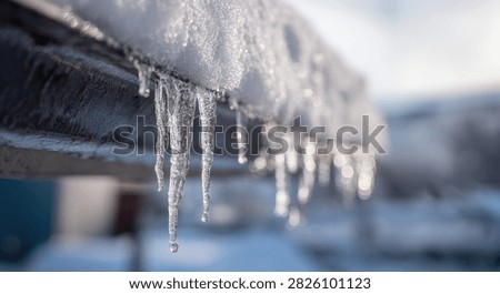 Detailed view of sharp icicles formed on a metal pipe, indicating freezing temperatures and winter weather.