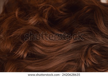Detailed view of shiny auburn hair highlighting its natural waves and texture background.