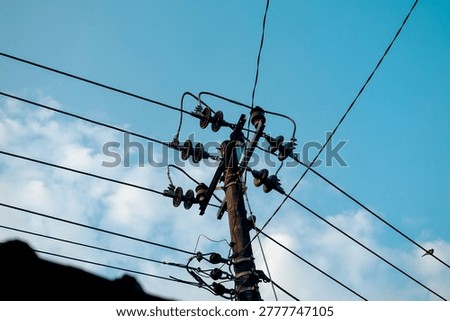 A detailed view of the upper section of a utility pole featuring interconnected electrical cables and ceramic insulators branching in multiple directions