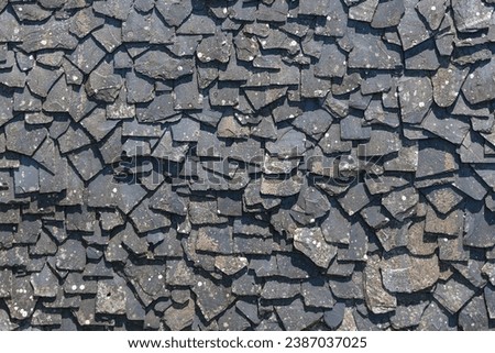 Detailed view of wall texture randomly lined with slate panels, typical and traditional shale stone material, used as external waterproof cladding in construction...