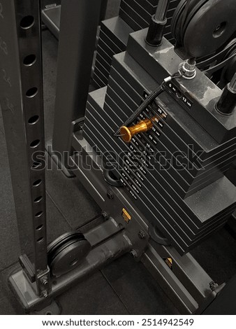 Detailed view of the weight stack on a cable machine in a gym, showing the pin insertion point for weight selection, part of the mechanism, and surrounding structure of the machine.