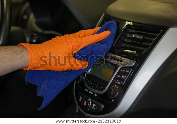 Detailing and car cleaning services,the\
concept of car washing and cleaning.A male worker in orange rubber\
gloves,cleaning the plastic of the car interior with a blue\
microfiber towel.Auto\
detailing.