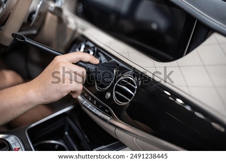 Detailing interior car dashboard using brush, ensuring thorough cleaning and high-quality finish