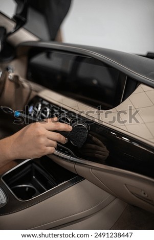 Detailing interior car dashboard using brush, ensuring thorough cleaning and high-quality finish