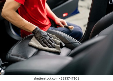 Detailing a man an employee of a car service station performs chemical cleaning and washing of a car with microfiber cloth