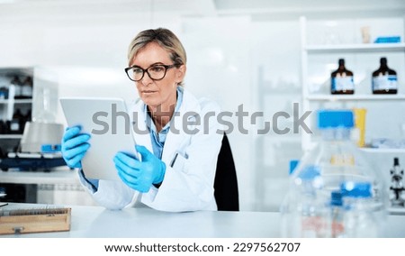 Detailing the process of her experiments. a mature scientist using a digital tablet in a lab.