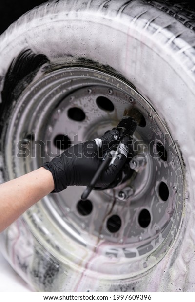 Detailing studio worker cleaning sport classic car\
wheel with brush