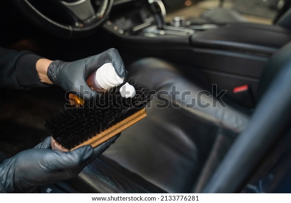 Detailing worker applies leather cleaning foam\
to the brush. Professional car\
detailing