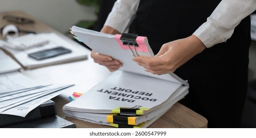 Detail-oriented professional sorting documents with binder clips and notes
