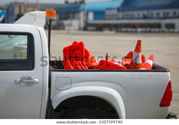 Details with the back of a truck\
carrying orange traffic safety cones on the runway of an\
airport