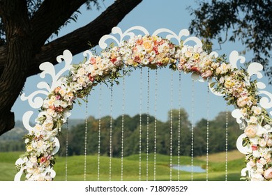 details of beautiful wedding arch of flowers on a background green field with trees