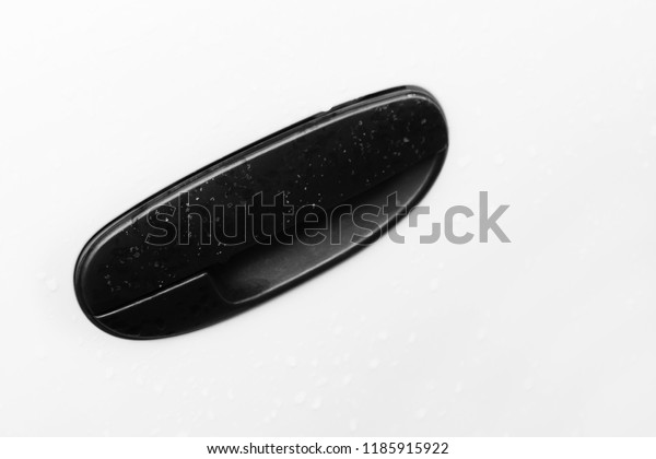The details of the car black door handle.\
White car door. Production of cars and their safety. Opening the\
car door. Unlocking. Raindrops on the\
surface.