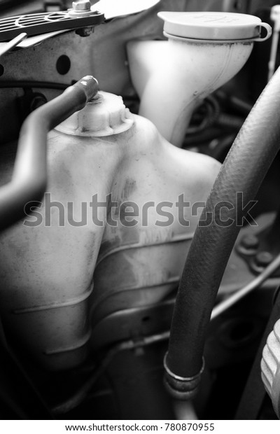 details of car engine, radiator tank\
and windshield washer tank, black and white\
photography
