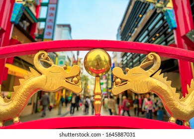 Details of chinese dragons on one of the gates of Yokohama Chinatown in Japan with people walking in narrow city on blurred backgroung.