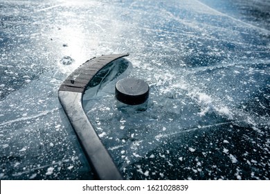 Details close up hockey puck on a frozen pond. Ice skating in nature at sunset in winter. Travel and sports
