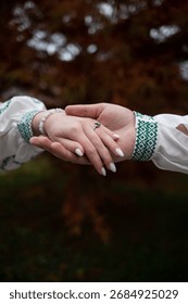 Details of devotion: the delicate ring, the elegant manicure, and the striking green ethnic pattern uniting two people.