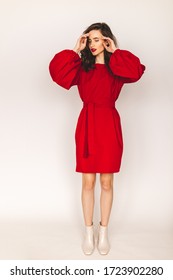 Details of everyday elegant look. Model wearing casual outfit. Red color short dress featuring long puff sleeves with cuffs in trendy minimalistic style. Lantern sleeves and dress. Girl fix hair.