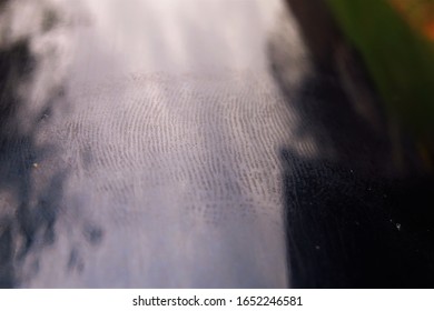 The Details Of A Finger Print On A Shiny Dark Blue Surface, As Well As Blurred Shadows From Nearby Objects. 