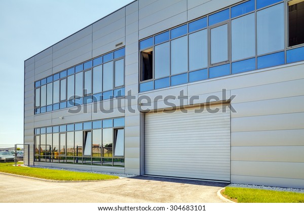 Details of gray facade made of\
aluminum panels  with doors and windows on industrial\
building