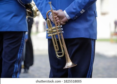 Details with the hands of a military fanfare member holding a brass wind musical instrument.