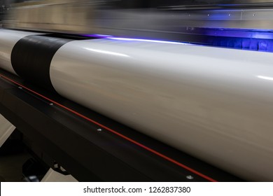 Details From The Inside Of A Large Scale Professional Printer, Print Head Passing By At Great Speed Over Vinyl Rolls During Production Hours. 