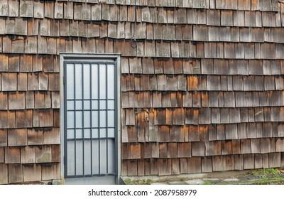 Details Of An Old Barn House In Country Side. Rustic Wall Patterns Of Weathered Cedar Shake Shingles With Door In Rural Area. Street View, Selective Focus, Nobody