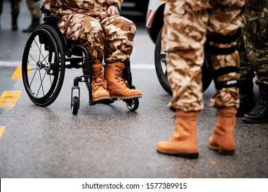 Details With A Romanian Army Veteran Soldier, Injured And Disabled, Sitting In A Wheelchair Dressed In His Military Desert Camouflage Uniform.