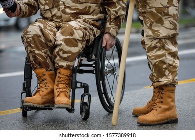 Details With A Romanian Army Veteran Soldier, Injured And Disabled, Sitting In A Wheelchair Dressed In His Military Desert Camouflage Uniform.