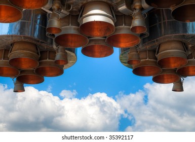 Details Of Space Rocket Engine Against Blue Sky With Clouds