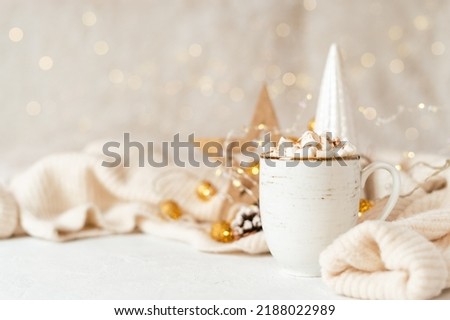 Details of Still life, cup of coffee with marshmallows, wooden eco natural decor, Christmas lights with sweater on white background, home decor in cozy house. Winter weekend concept with copy space