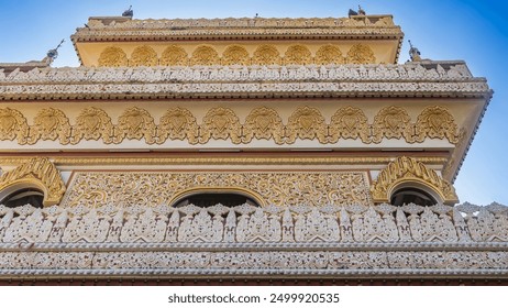 Details of the temple's architecture. Tiers of terraces with openwork carved ornaments. Gilded patterns on the walls. The background is a clear blue sky. Dhammikarama burmese temple. Malaysia. Penang. - Powered by Shutterstock