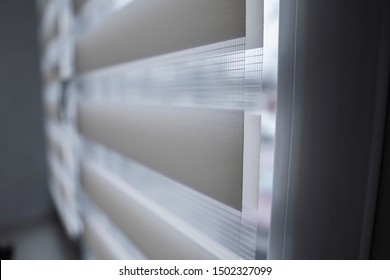 Details Of White Fabric Roller Blinds On The White Plastic Window In The Living Room. Close Up On Roll Curtains Indoor.