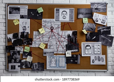 Detective board with fingerprints, photos, map and clues connected by red string on white brick wall - Shutterstock ID 1897738369