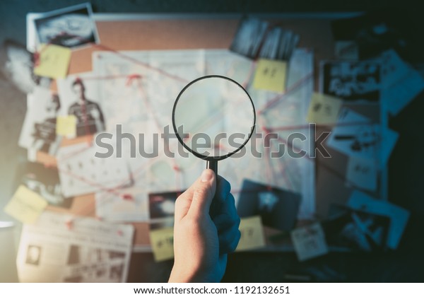 偵探手拿著放大鏡在板前面的證據 犯罪現場照片和地圖 高對比度圖像庫存照片 立刻編輯