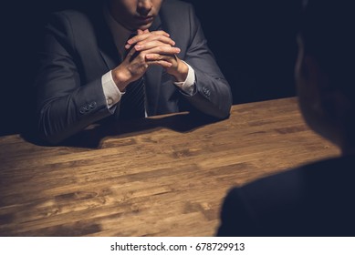 Detective interviewing suspect in dark room - investigation and interrogation concepts - Shutterstock ID 678729913