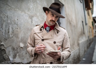 Detective Journalist Writing On A Notebook While Standing Against An Old Wall