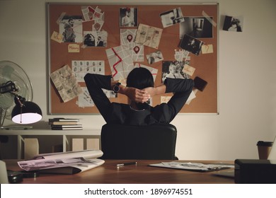 Detective Looking At Evidence Board In Office, Back View