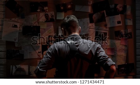Detective looking at investigation board, searching for solution, back view