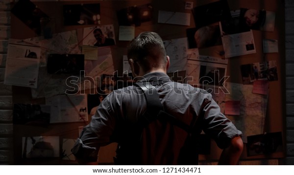 Detective looking at investigation board, searching\
for solution, back\
view